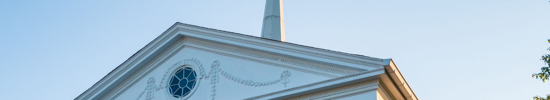 Exterior detail shot of Catonsville Presbyterian Church, showing roofline, decorative window, and steeple.