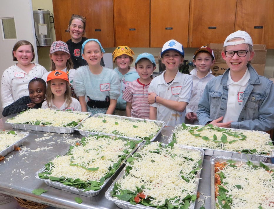 Elementary school youth smile with the casseroles they assembled for the shelter
