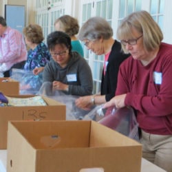 An assembly line packs Safe Motherhood Kits from boxes of supplies.