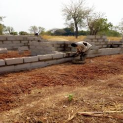 A construction worker builds a concrete block wall in Nigeria.