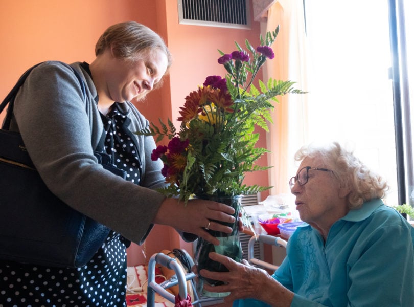 A woman delivers flowers to an elderly woman